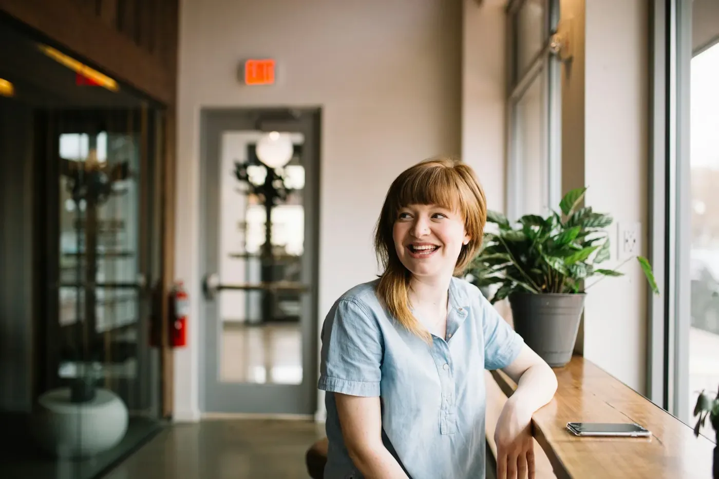 Smiling lawyer working by a bright window, signing off ads faster with Voxly Vision compliance checks
